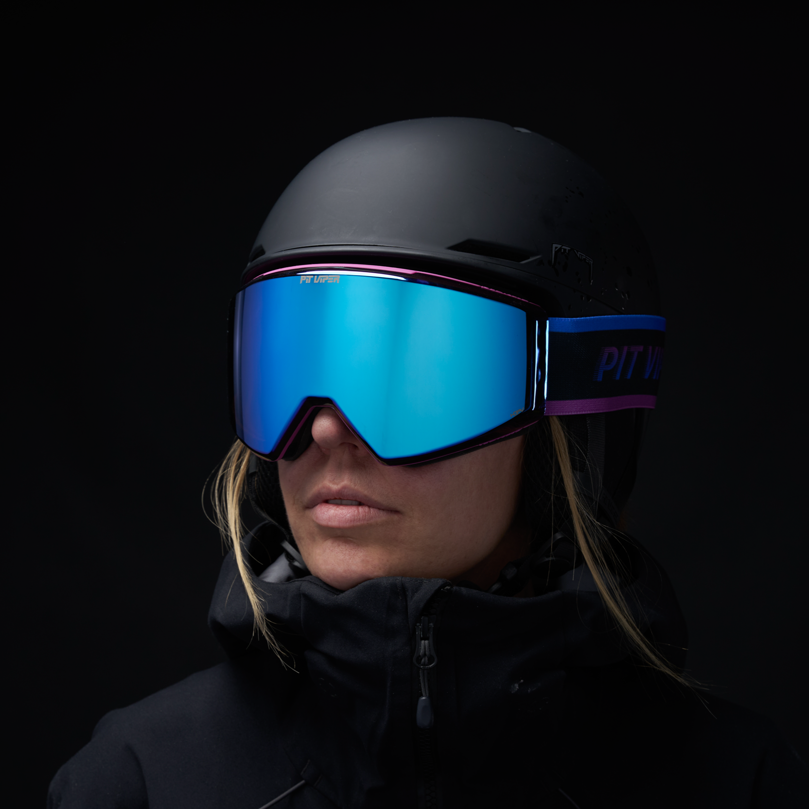 Person wearing a black helmet and blue goggles against a dark background
