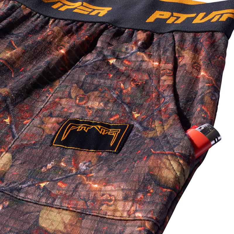 | its_a_pocket.JPG | Close-up of camouflage-patterned shorts with a black waistband featuring orange lettering and a black patch with orange branding on the left leg.
