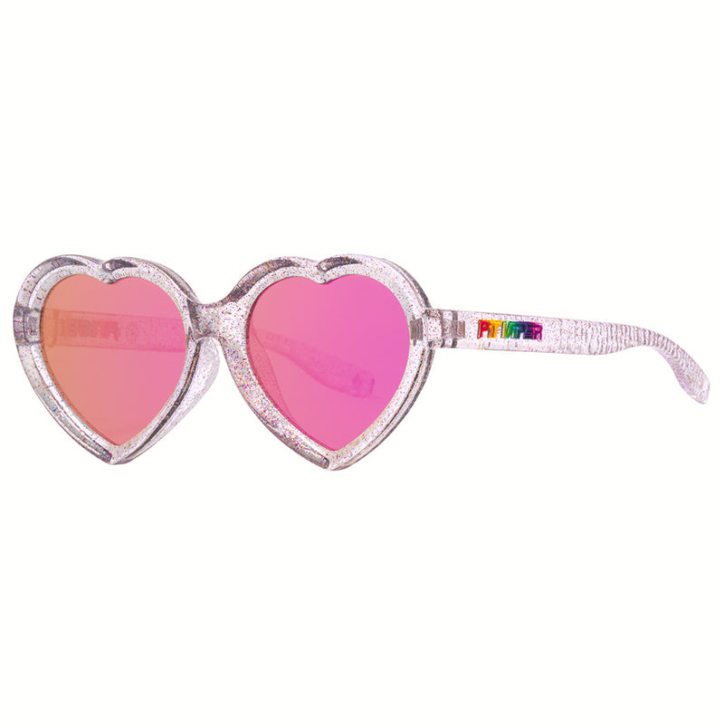 Pink | side_view.JPG | Heart-shaped novelty sunglasses with glittery silver frames, pink mirrored lenses, and a rainbow-colored 'PRIDE' logo on the temple arm, shown against a plain white background.