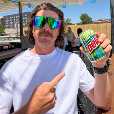 Man holding a soda can while wearing green sunglasses.