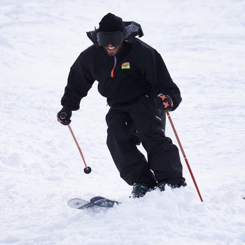 / Smoke | weeeee.JPG | A person skiing through deep snow, wearing a black ski jacket, black ski pants, black gloves, a black beanie, and black goggles, holding red ski poles.