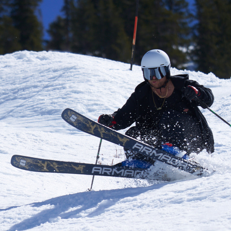 | photo_of_the_chuck.JPG | A skier in a black jacket, white helmet, and goggles carving through fresh snow, with Armani Armani skis visible and pine trees in the background.