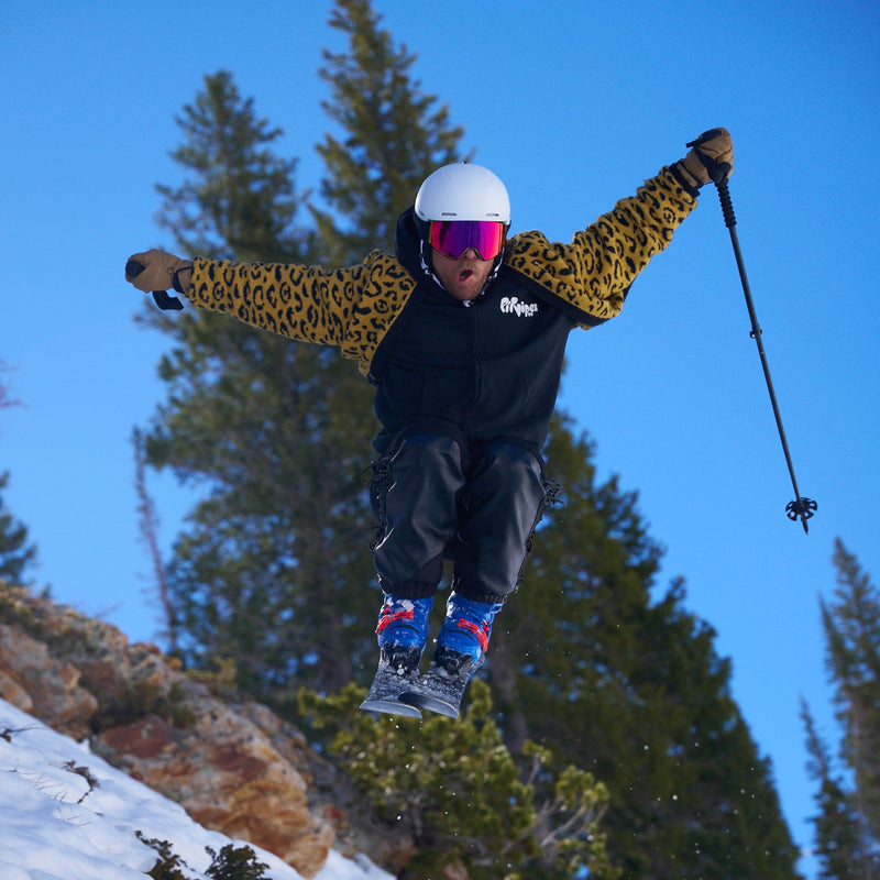 HDPV Red | photo_of_chuck.JPG | Photo of bearded man wearing a leopard print sweater, a white ski helmet and blue ski boots catching air while also wearing the BN 5000 Goggles from Pit Viper.