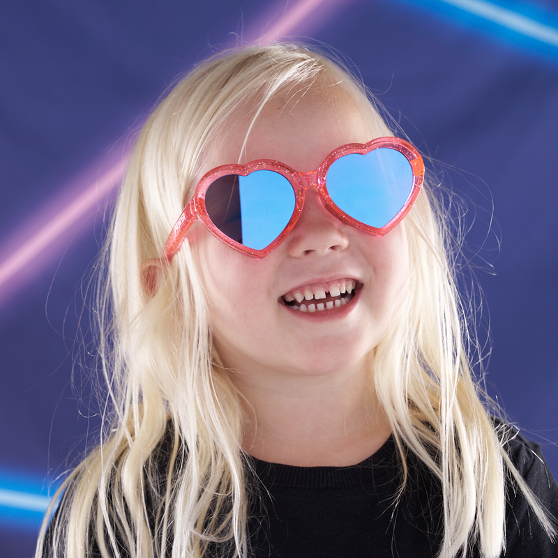 Blue-Purple | smile!.JPG | A young girl with long blonde hair wearing heart-shaped red glittery sunglasses with blue mirrored lenses, set against a dark blue background with neon light streaks.