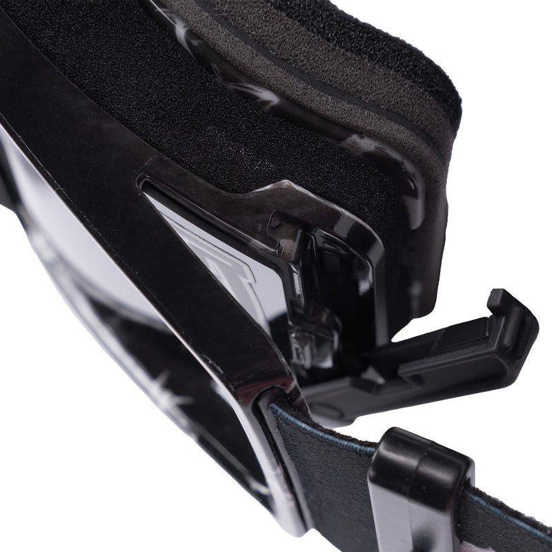 Silver | it_a_latch.JPG | Close-up detail of black protective goggles showing the strap buckle, transparent lens edge, and textured foam padding against a white background.